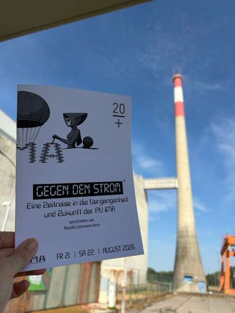 Foto des Programmhefts vor dem AKW und strahlend blauem Himmel