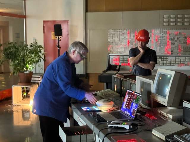 Foto von Anne Wellmer, die in der Schaltwarte live auf der Sprechmaschine spielt. Neben ihr steht Jakob Scheidt, der die Maschine vor 20 Jahren zur ersten Ausstellung des IMA, 'Zauberhafte Klangmaschinen' gebaut hat. Es ist ein Nachbai der Sprechmaschine von Kempelen aus dem Jahr 1791.