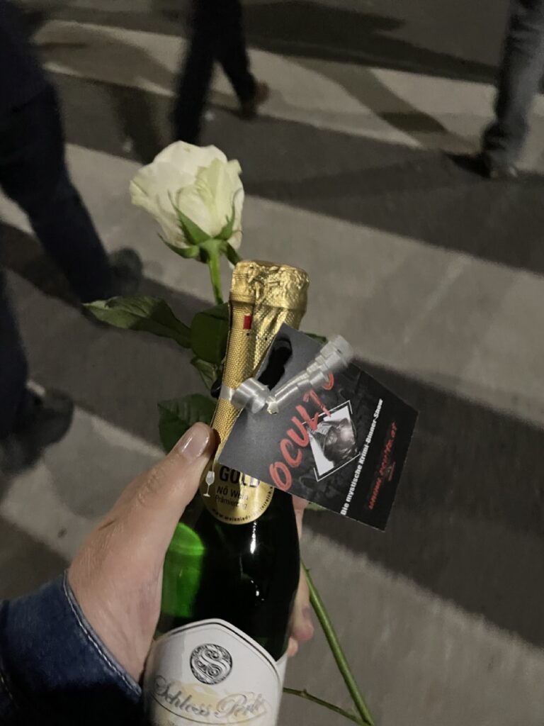 Foto einer kleinen Flasche Sekt und einer weißen Rose in meiner Hand. Beides Premierengeschenke.